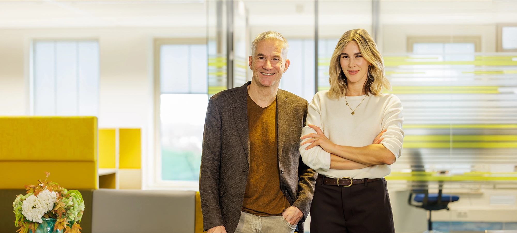 Decoratieve foto van een mannelijke en vrouwelijke collega van de Regionale Belasting groep, welke direct in de camera kijken.