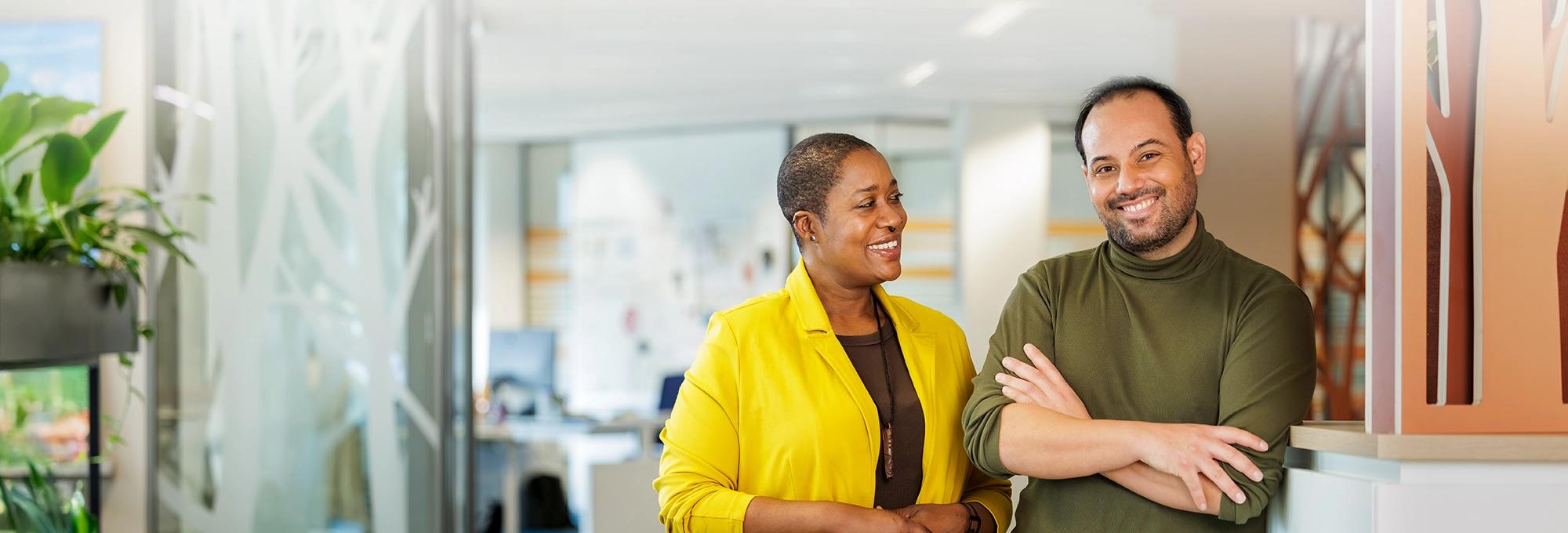 Decoratieve foto van een mannelijke en vrouwelijke collega van de Regionale Belasting groep, welke direct in de camera kijken.